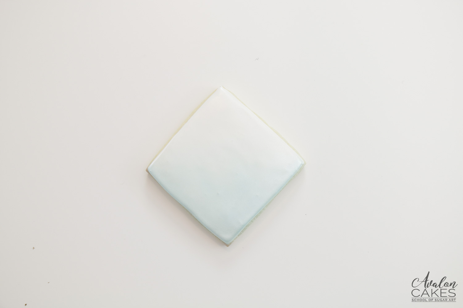Square cookie with white royal icing and airbrushed blue 