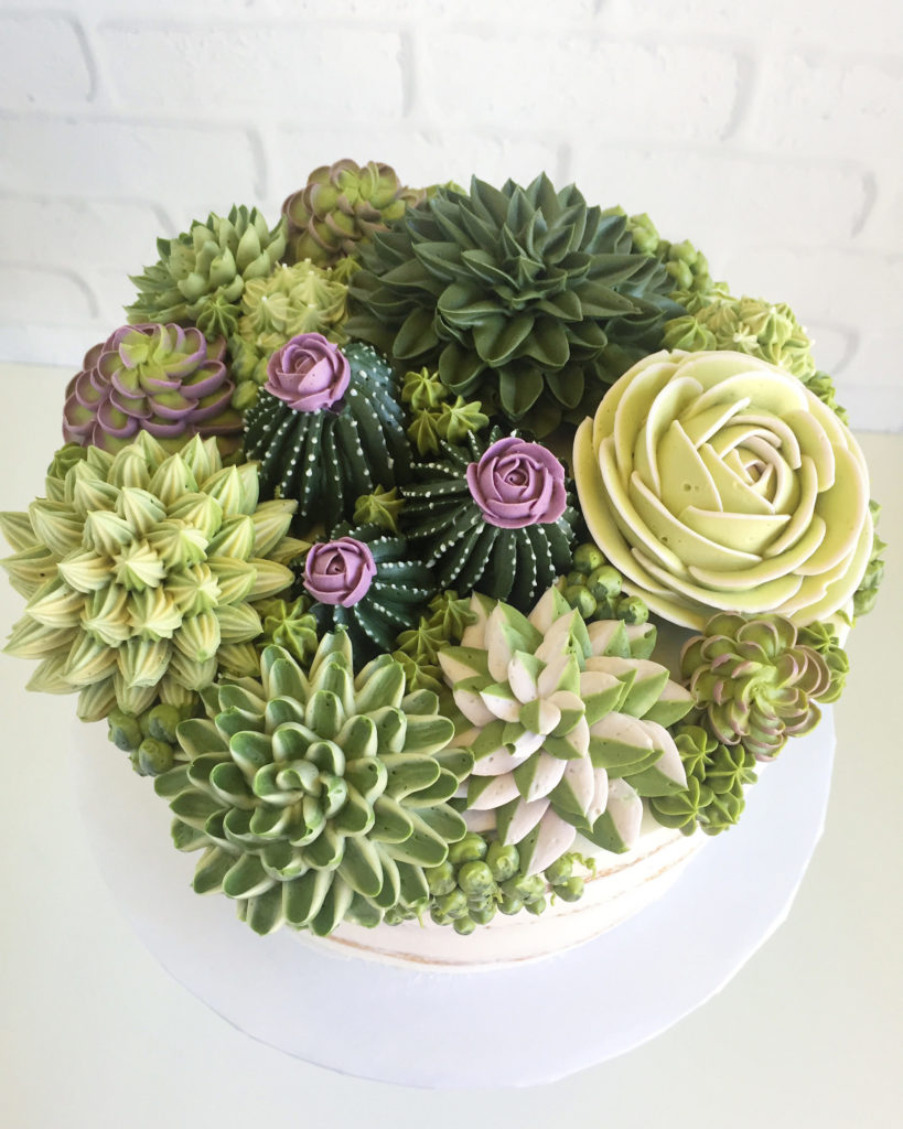 Overhead shot of tones of bright green buttercream piped succulents on top of a round cake